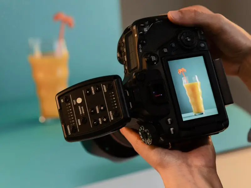 Quelqu'un qui prend en photo un verre de jus avec un appareil photo professionnel noir